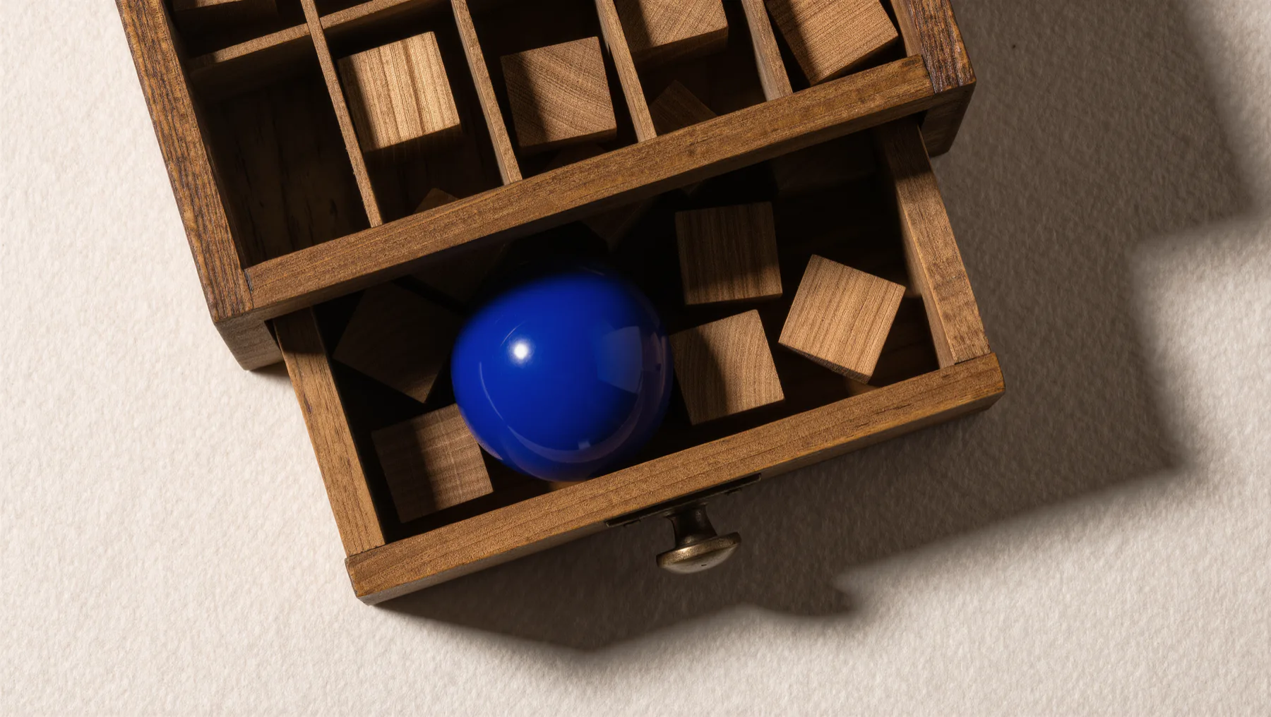 Old typesetter's case with compartments and wooden blocks, a cobalt-blue sphere inside