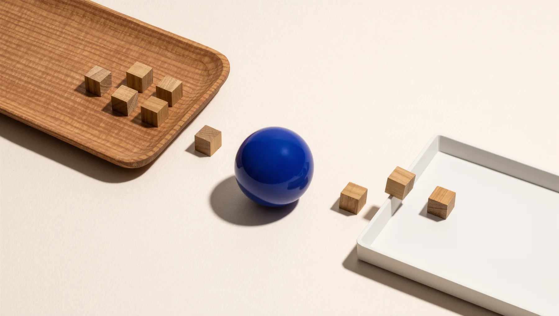 Wooden blocks moving from a wooden tray into a white tray, a cobalt-blue sphere between them