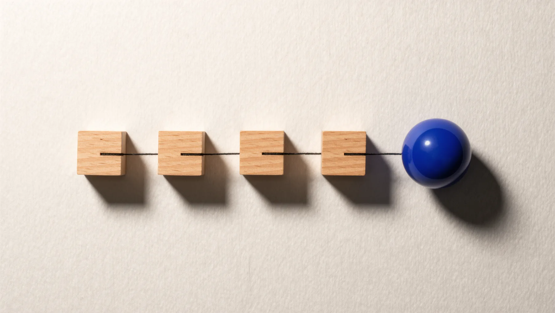 Wooden blocks in a row, connected by a thread, a cobalt-blue sphere at the end